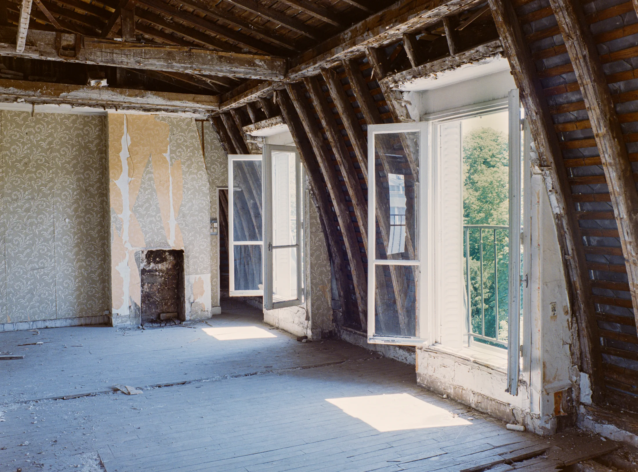 Stripped attic room with exposed roof timbers and open windows