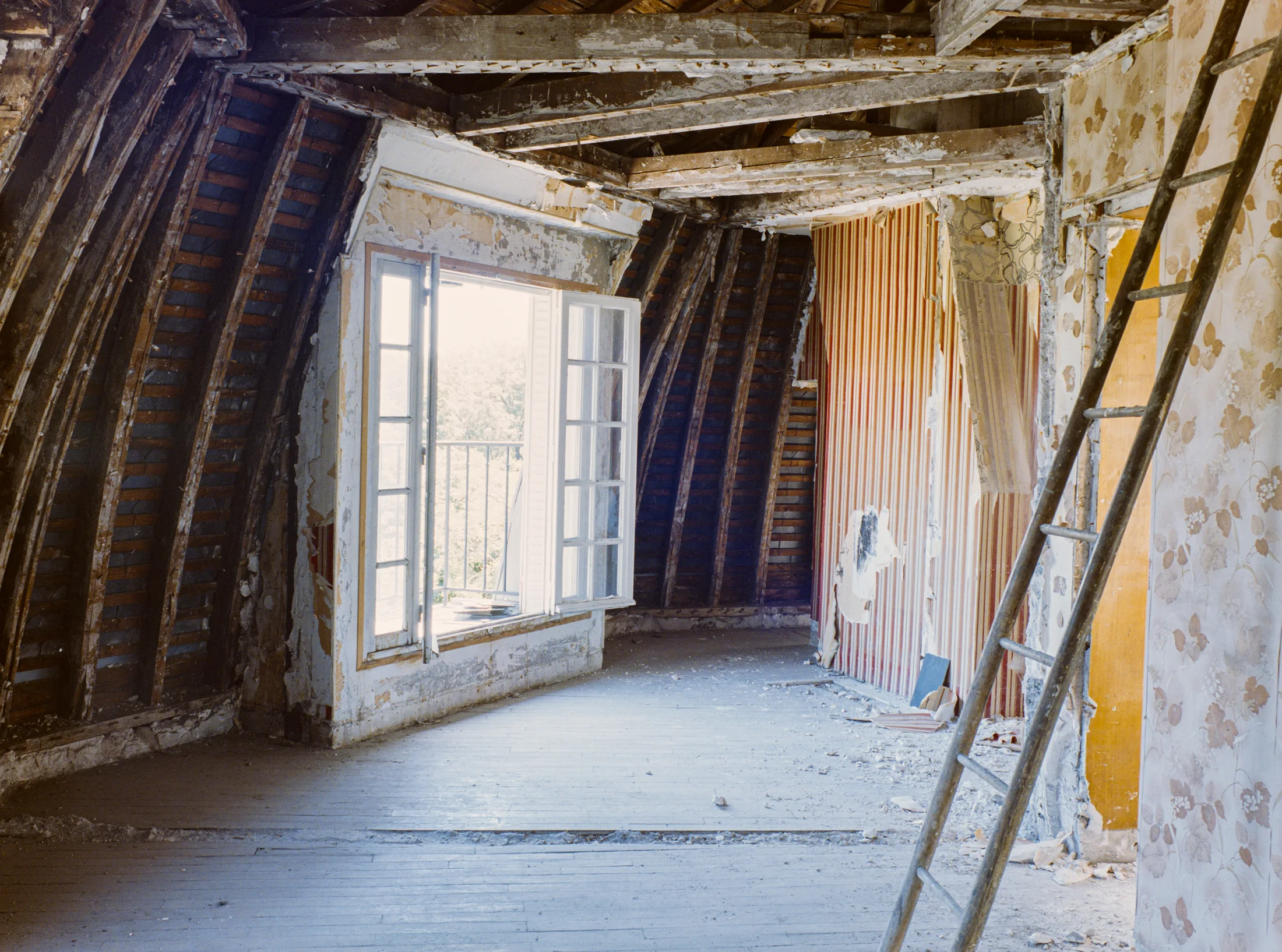 Stripped attic interior with a ladder and exposed rafters